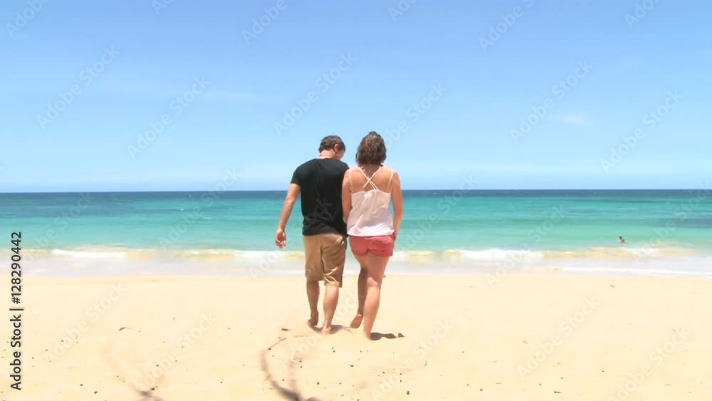 Happy woman and man couple walk together, hold hands, reach ocean shore and kiss.