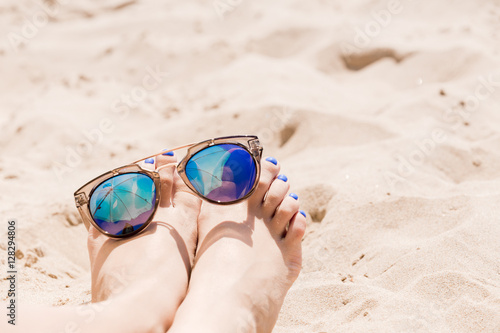 Sunglasses are on the legs on the beach