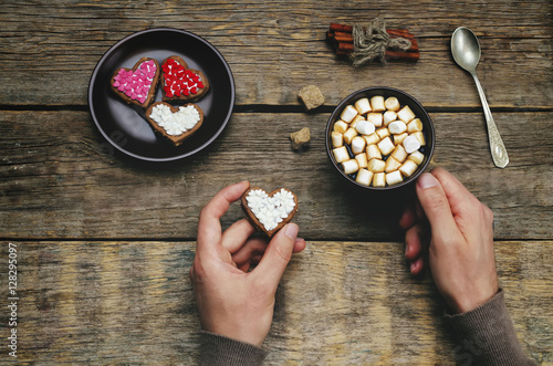 Male hands holding cookie in the forms of heart and a cup of cof