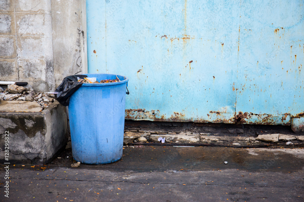 Blue garbage bin in front of blue factory door. Blue garbage bin in front of blue factory door.