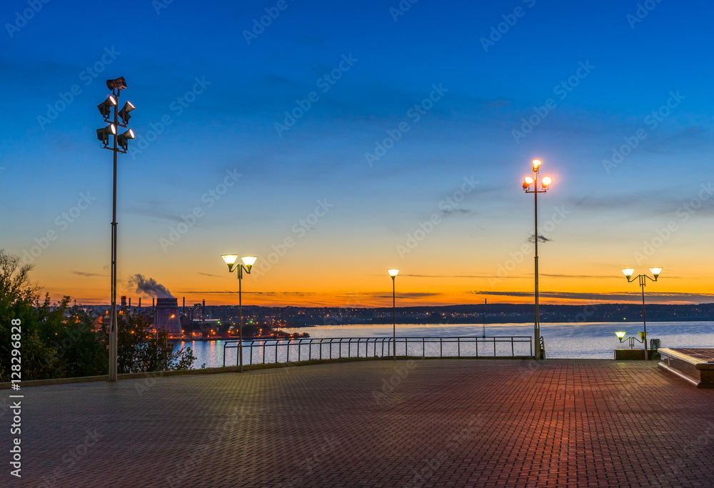 Embankment illuminated by lanterns at sunset