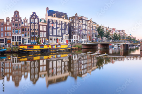 Amsterdam canal Singel with typical dutch houses, bridge and houseboats during morning blue hour, Holland, Netherlands.