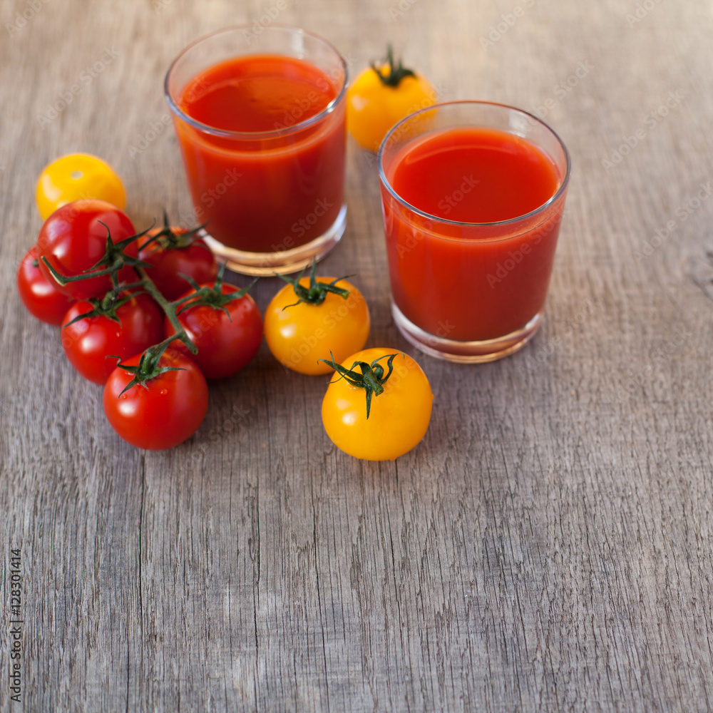 Two glasses of tomato juice on the grey wooden table, selective focus on tomato, square Two glasses of tomato juice on the grey wooden table, selective focus on tomato, square
