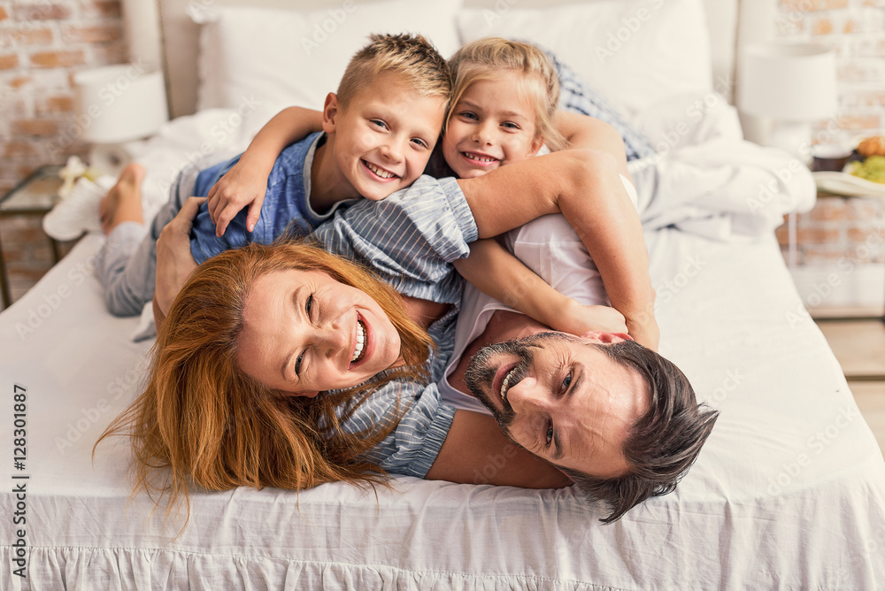 Fototapeta premium Happy parents and kids enjoying their morning in bed