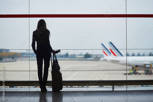 Young woman in the airport, looking through the window at planes