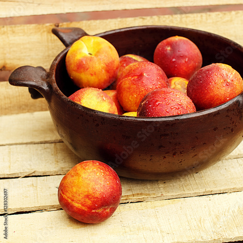 Bowl with fresh peaches on wooden background