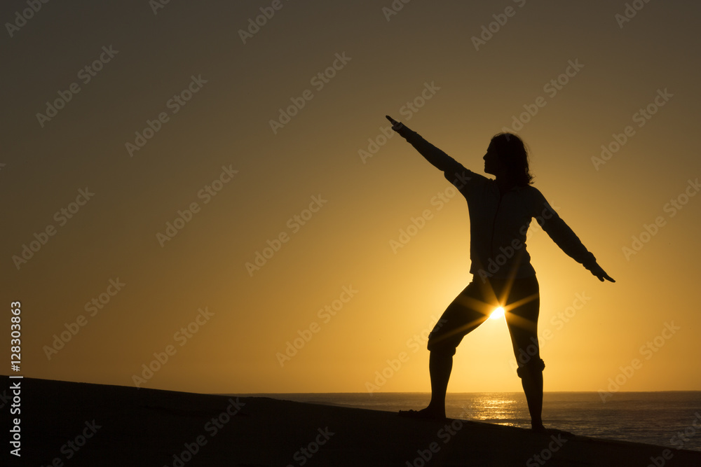 Silhouette of female form with sun star on beach in Mexico
