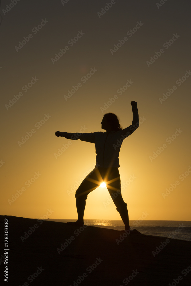 Silhouette of female form with sun star on beach in Mexico