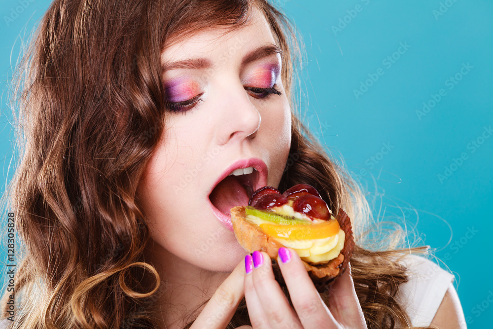 Cute girl holds fruit cake in hand on blue Cute girl holds fruit cake in hand on blue