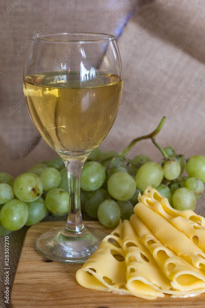 still life with glass of white wine, cheese and grapes on wooden background still life with glass of white wine, cheese and grapes on wooden background