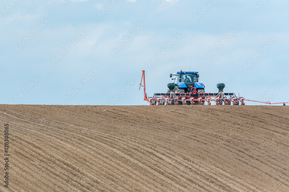 Large view on the tractor harrowing the field in spring season Large view on the tractor harrowing the field in spring season