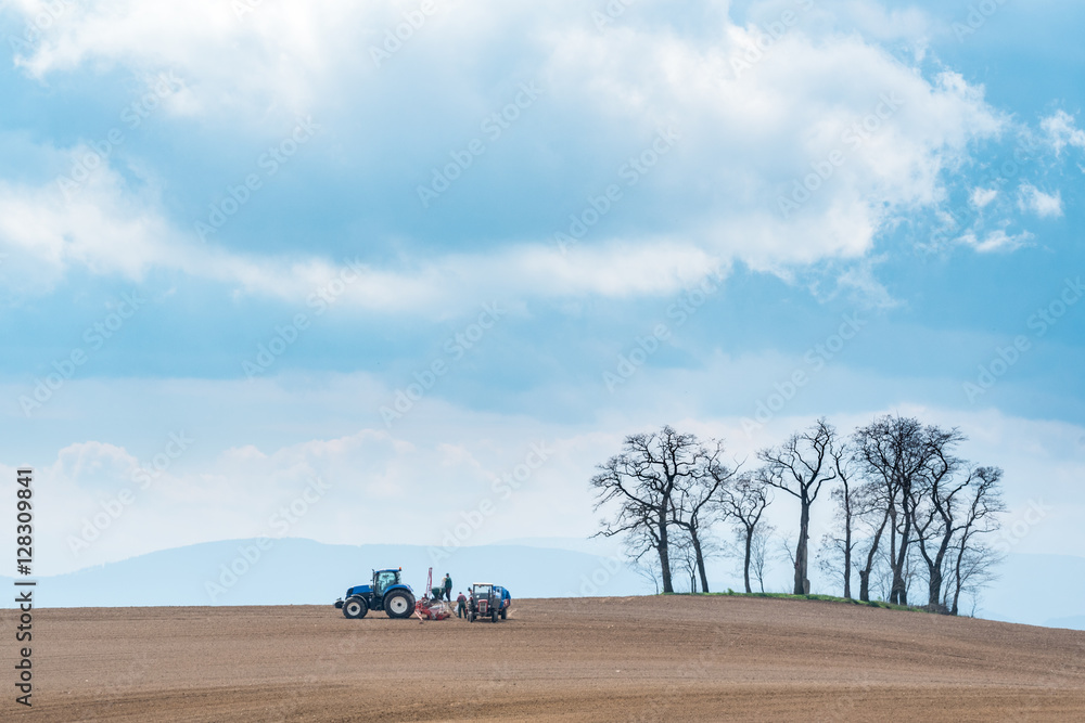 Large view on the tractor harrowing the field in spring season Large view on the tractor harrowing the field in spring season