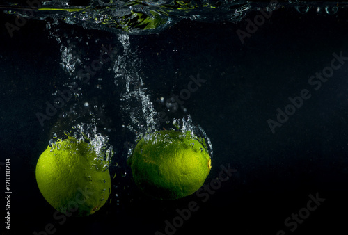 Lime splashing in water on black background