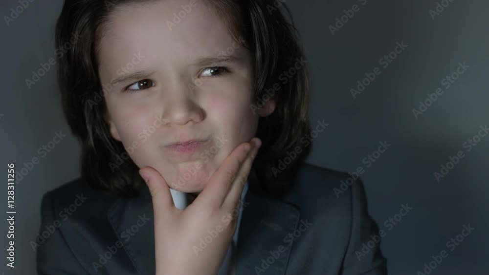 4k shoot of a cute child posing as a business man in studio thinking 4k shoot of a cute child posing as a business man in studio thinking