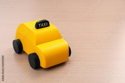 Yellow toy taxi cab on wooden background