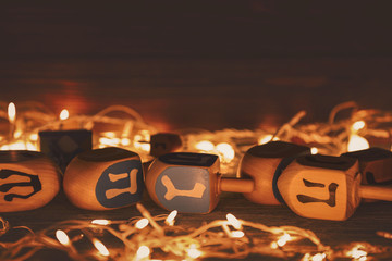 Composition of dreidels for Hanukkah and garland on wooden table