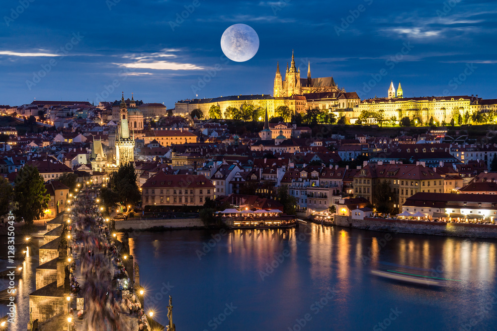 Fototapeta premium Full moon over Prague skyline at night. Magnificent Charles brigde and Prague castle at night along the River Vltava. Czech Republic