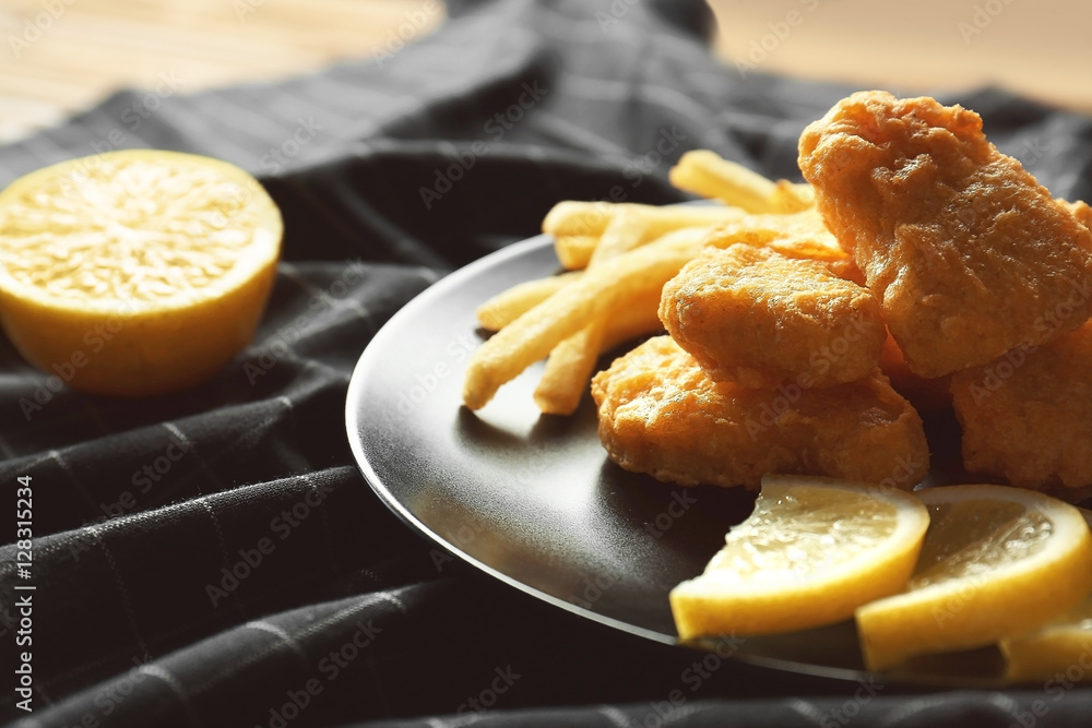Tasty chicken nuggets with fries and lemon on plate Tasty chicken nuggets with fries and lemon on plate