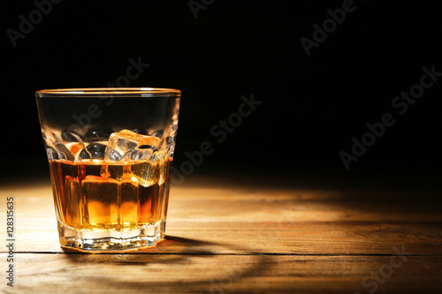 Glass of whisky on wooden table closeup