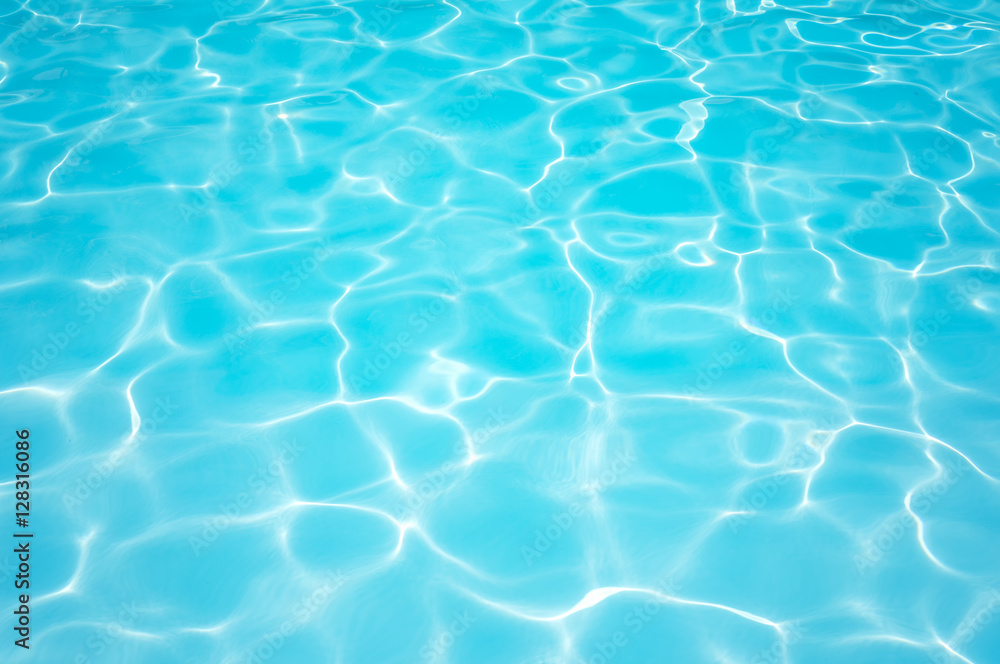 Ripple blue water surface in swimming pool with sun reflection