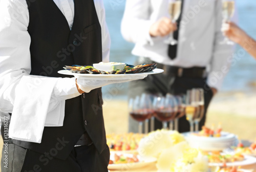Waiter holding plate with tasty mussels, close up view