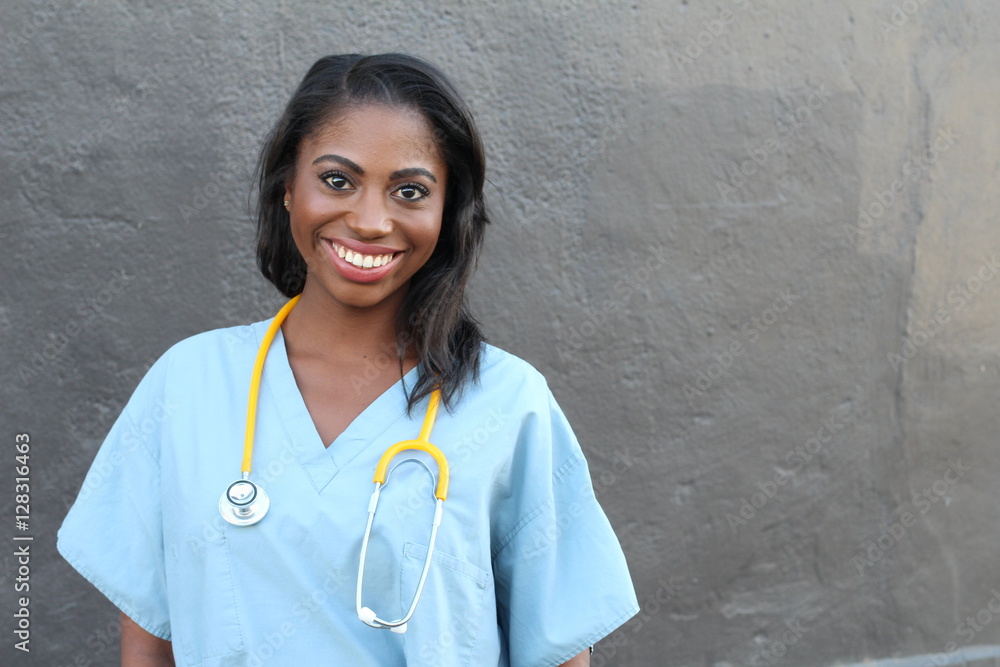 Female African American doctor or nurse smiling isolated over dark background Female African American doctor or nurse smiling isolated over dark background