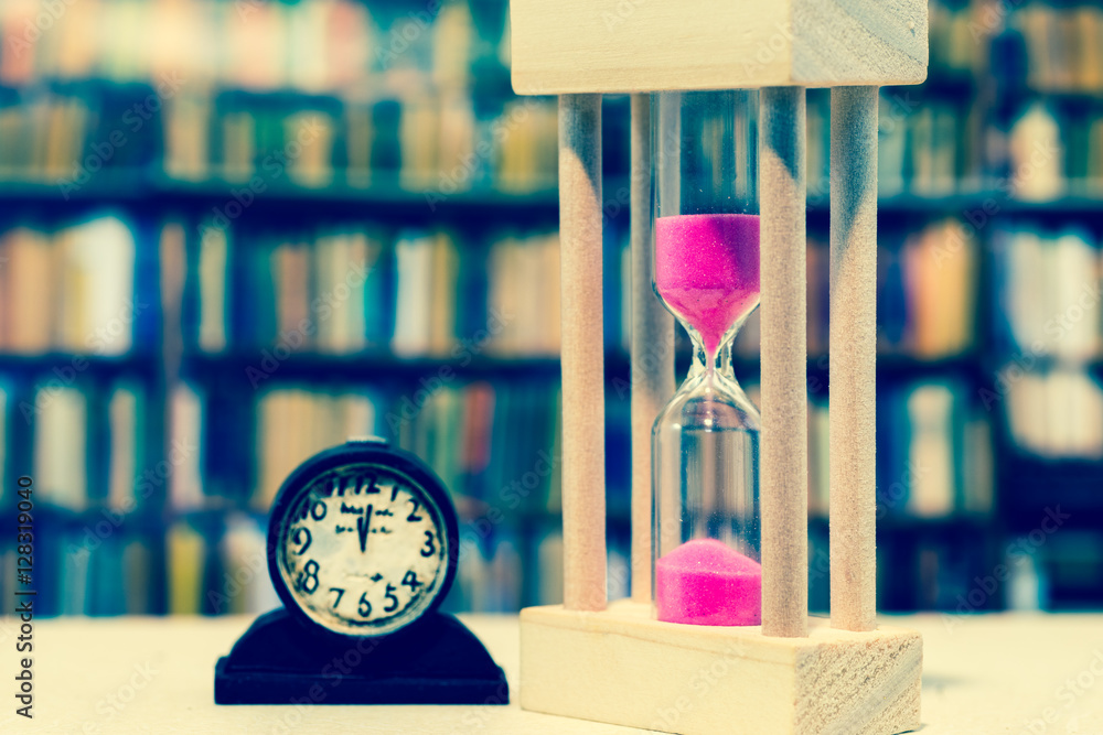 Fototapeta premium Hourglass against bookshelf