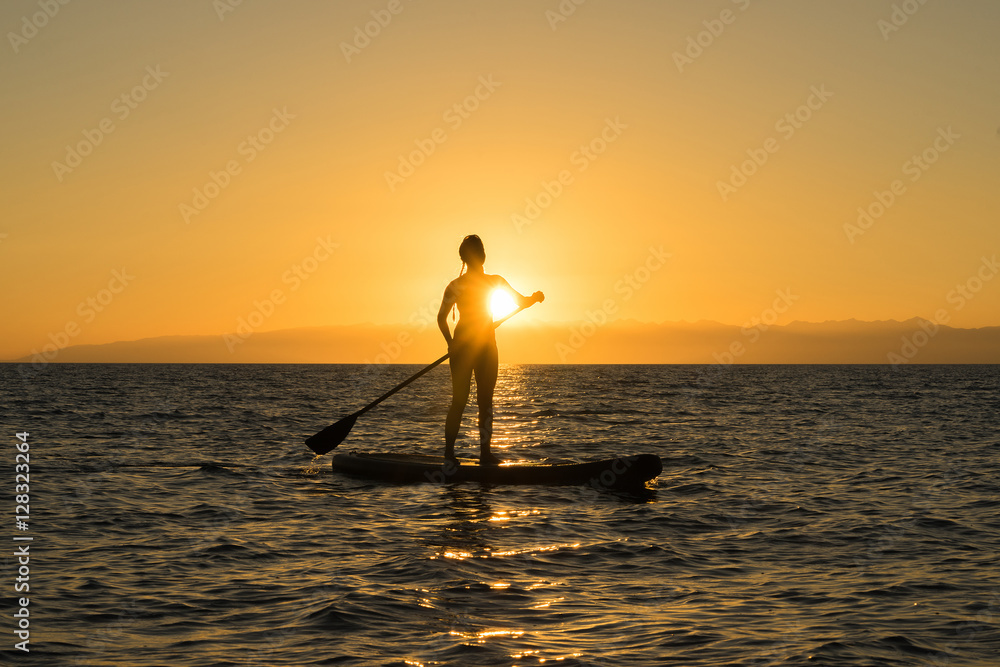 woman on sup board in sunset