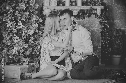 Happy young couple celebrating Christmas near the fireplace