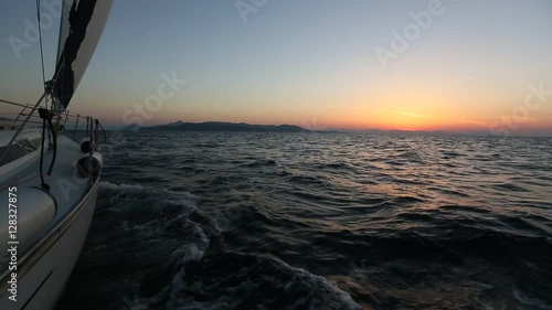 Magic sunset at sea shot of a luxery yacht boat. Sailing in the wind through the waves.