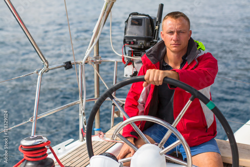Skipper at the helm controls of a sailing yacht. Lifestyle, sport and leisure. © De Visu