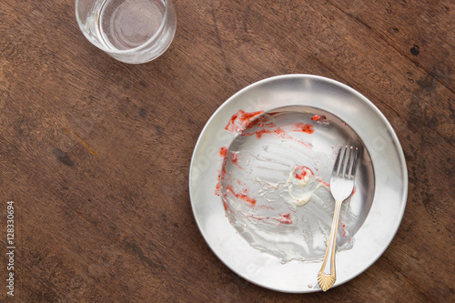 Empty plate and fork of dessert after meal on wooden table