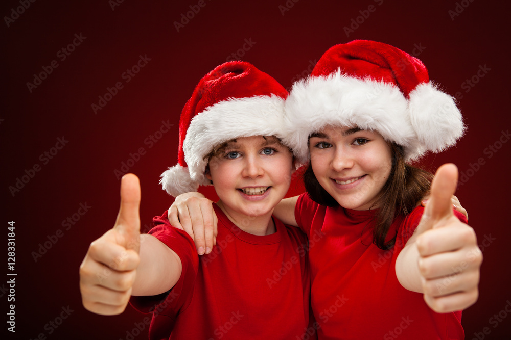 Christmas time - girl and boy with Santa Claus Hat showing OK sign Christmas time - girl and boy with Santa Claus Hat showing OK sign