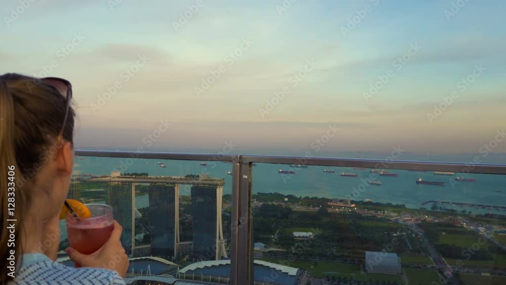 Woman drinking cocktail with view of Singapore Woman drinking cocktail with view of Singapore
