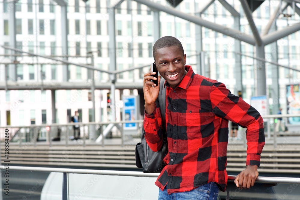 Happy young guy at railway station using cell phone