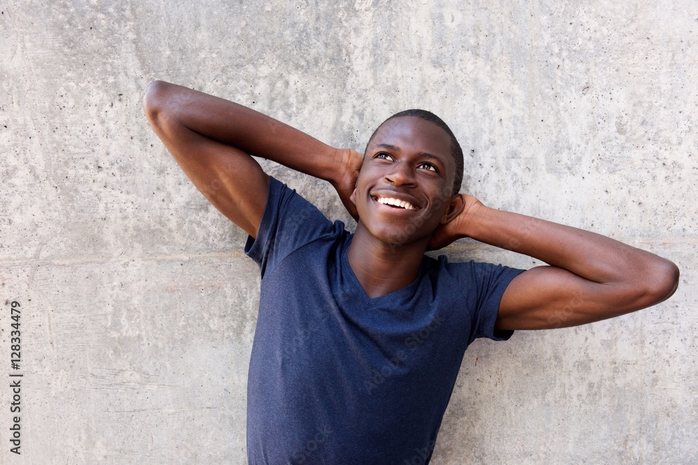 Obraz premium Young african man with hands behind head and looking up