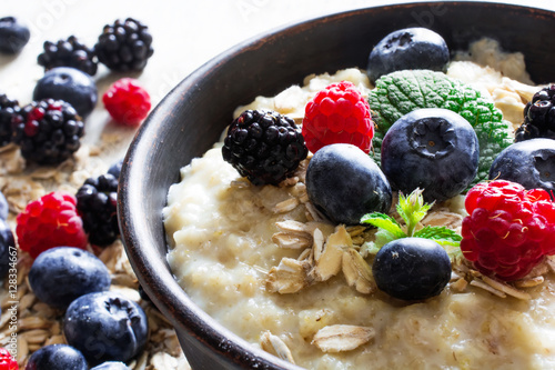 oatmeal porridge in ceramic bowl with fresh ripe berries