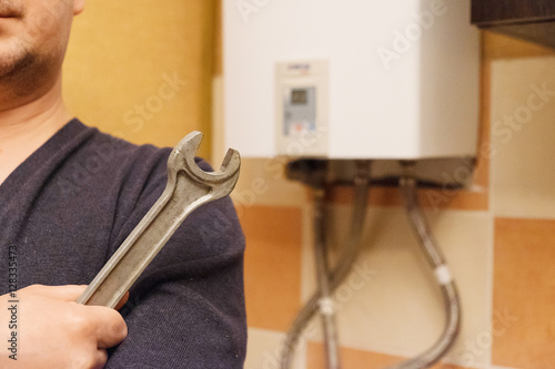 male hand holding a wrench on the background gas heater. concept repair gas water heater and other household appliances. focus on wrench