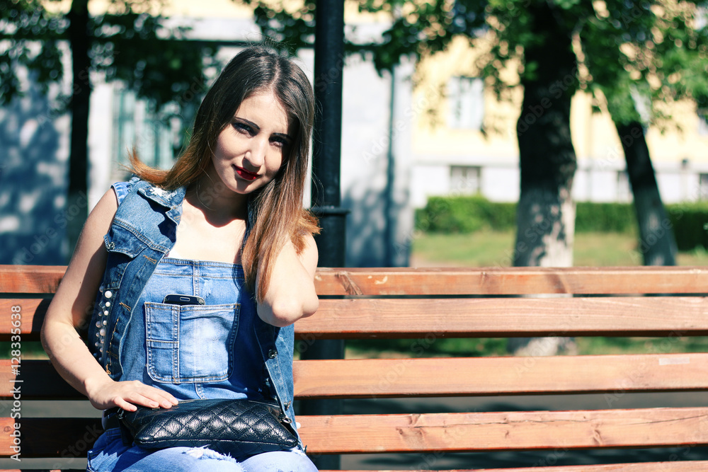 Brown haired young woman sits on a bench