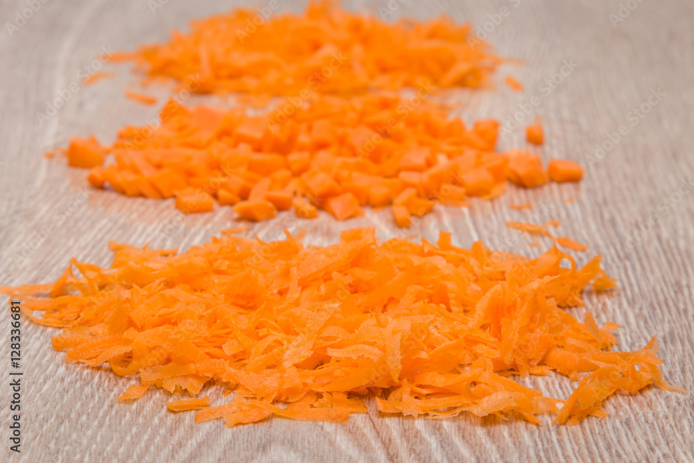 Cut and grated carrot on the wooden table in the kitchen. Healthy eating and lifestyle. Cut and grated carrot on the wooden table in the kitchen. Healthy eating and lifestyle.