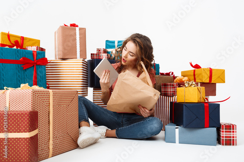 Young beautiful curly girl sitting on floor among gift boxes opening presents Isolated