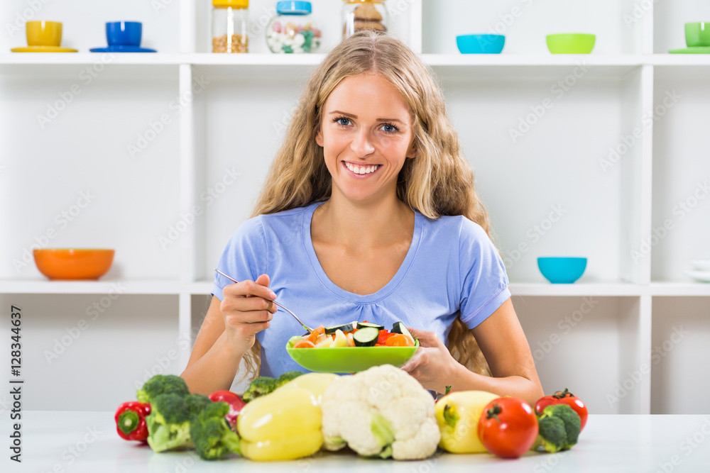 Beautiful girl enjoys eating vegetable salad at her home. Beautiful girl enjoys eating vegetable salad at her home.