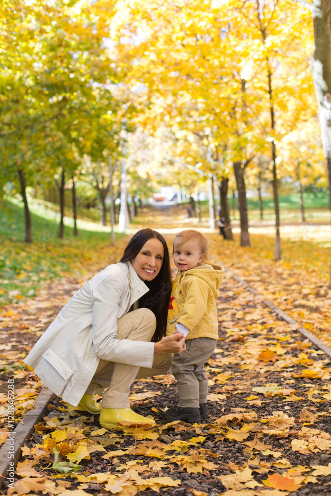 Mother and child playing with leaves in autumn park Mother and child playing with leaves in autumn park
