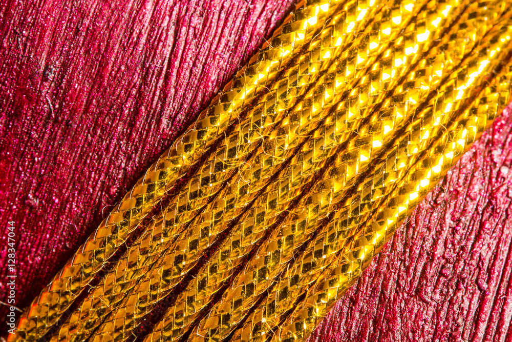 Fototapeta premium Gold thread on red texture background. Christmas gift, close up.