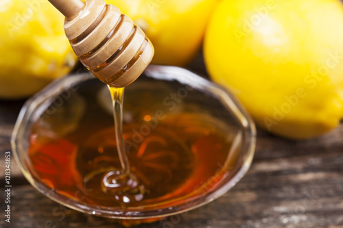 Bowl of sweet honey and lemons on wooden table.