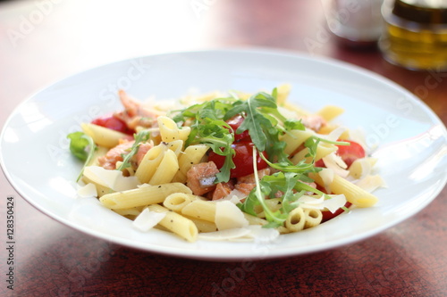 Restaurant food with fresh ingredients - pasta with dried tomatoes, parmesan and fresh rucola