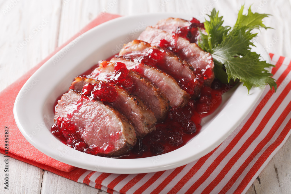 Tasty sliced roast duck breast with cranberry sauce close-up. horizontal