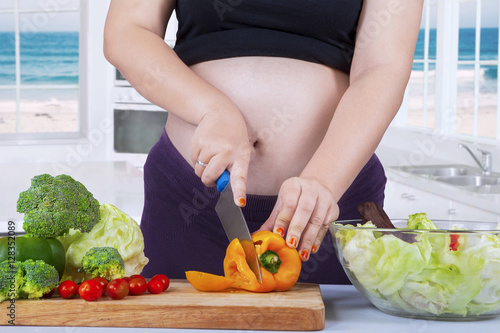 Expectant woman cuts fresh paprika