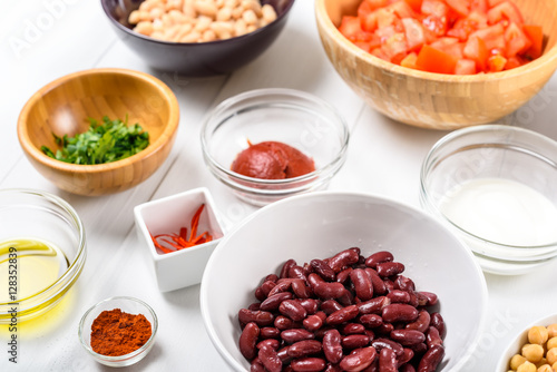 White And Red Kidney Beans, Chili Pepper, Paprika, Parsley, Olive Oil, Ketchup, Tomatoes And Yogurt Food Ingredients On White Wood Table