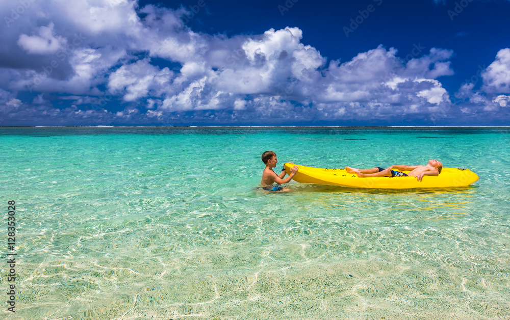 Two young caucasian boys kayaking at tropical sea on yellow kaya Two young caucasian boys kayaking at tropical sea on yellow kaya